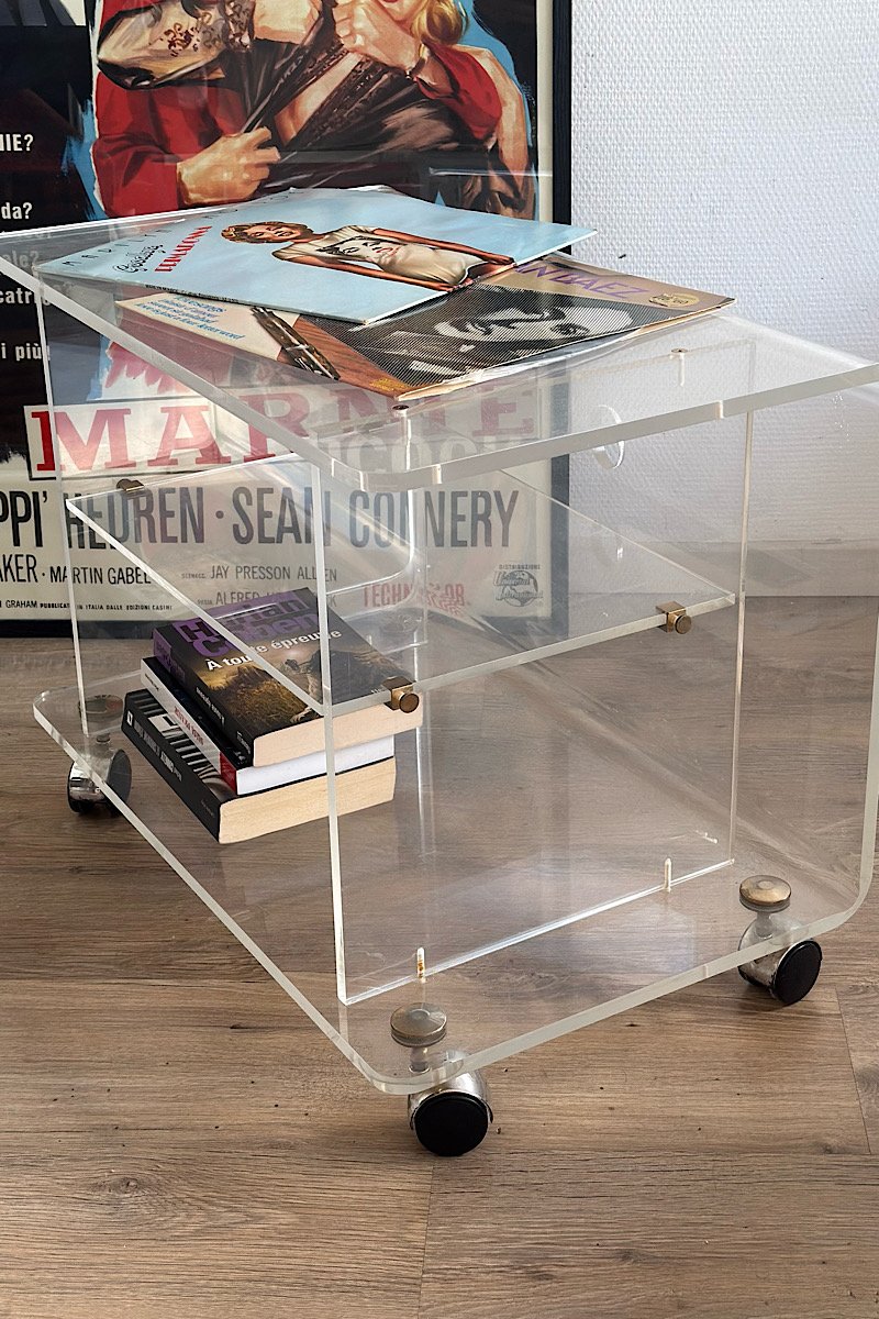 vue de profil d'une table basse en plexiglas sur roulettes. Des vinyles sont posés sur le plateau