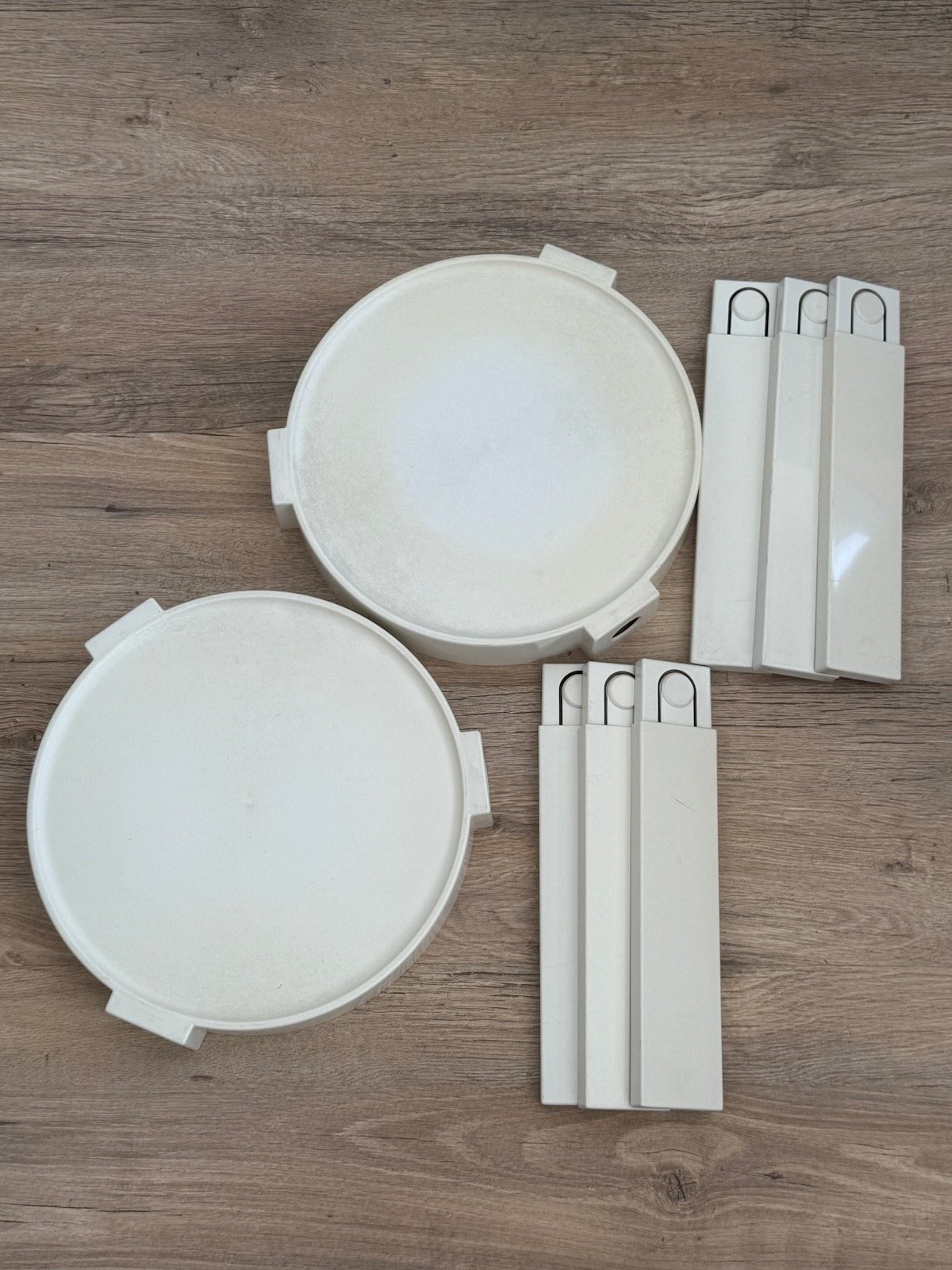 Vue du dessus de deux tables Prisunic blanches en plastique, démontées avec les pieds et les plateaux cote a cote