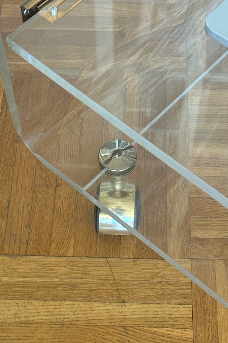 Gros plan sur l'une des roulettes pivotantes fixée à la structure en plexiglas transparent, posée sur un parquet ancien
