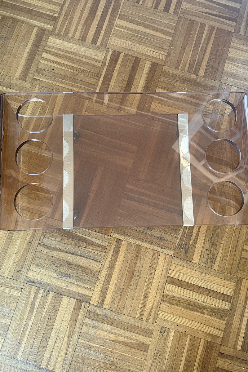 Plateau supérieur d'une table basse bar Michel Dumas vintage en plexiglas teinté, montrant les emplacements ronds pour les bouteilles.