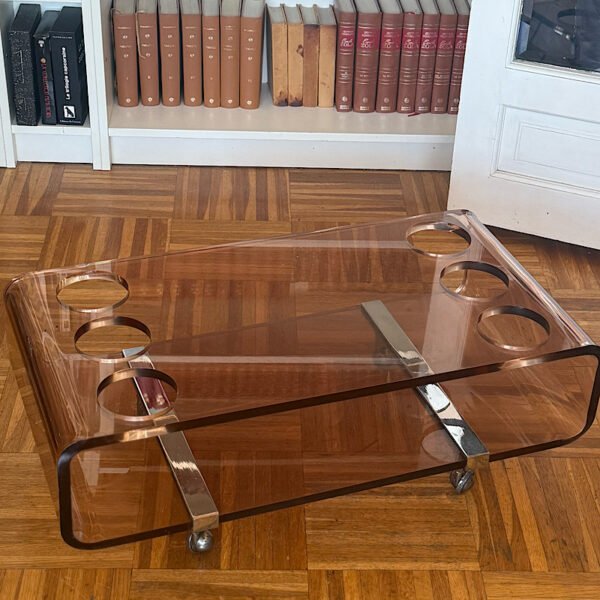 Vue de trois quarts d'une table basse bar Michel Dumas vintage en plexiglas fumé avec ses rangements pour bouteilles intégrés.