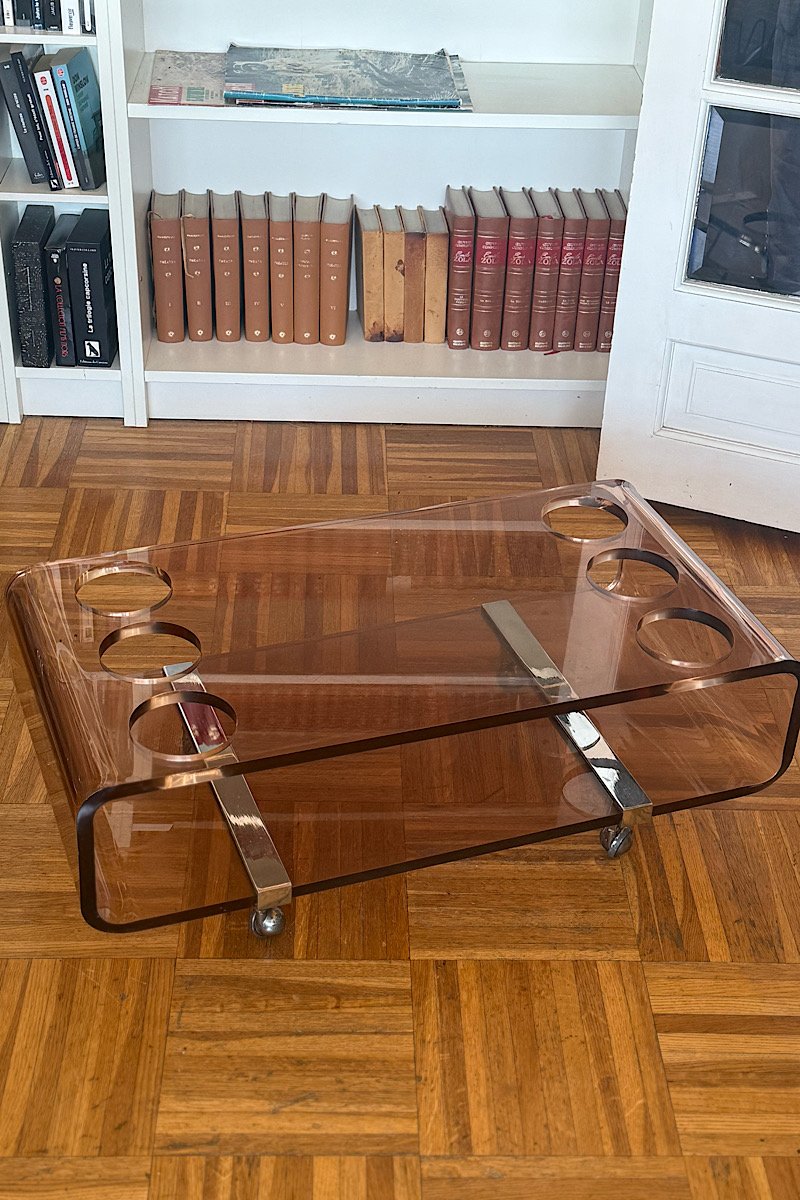 Vue de trois quarts d'une table basse bar Michel Dumas vintage en plexiglas fumé avec ses rangements pour bouteilles intégrés.