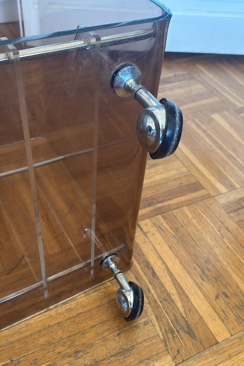 Gros plan sur les roulettes métalliques chromées fixées à la structure en plexiglas transparent d'un meuble de rangement.
