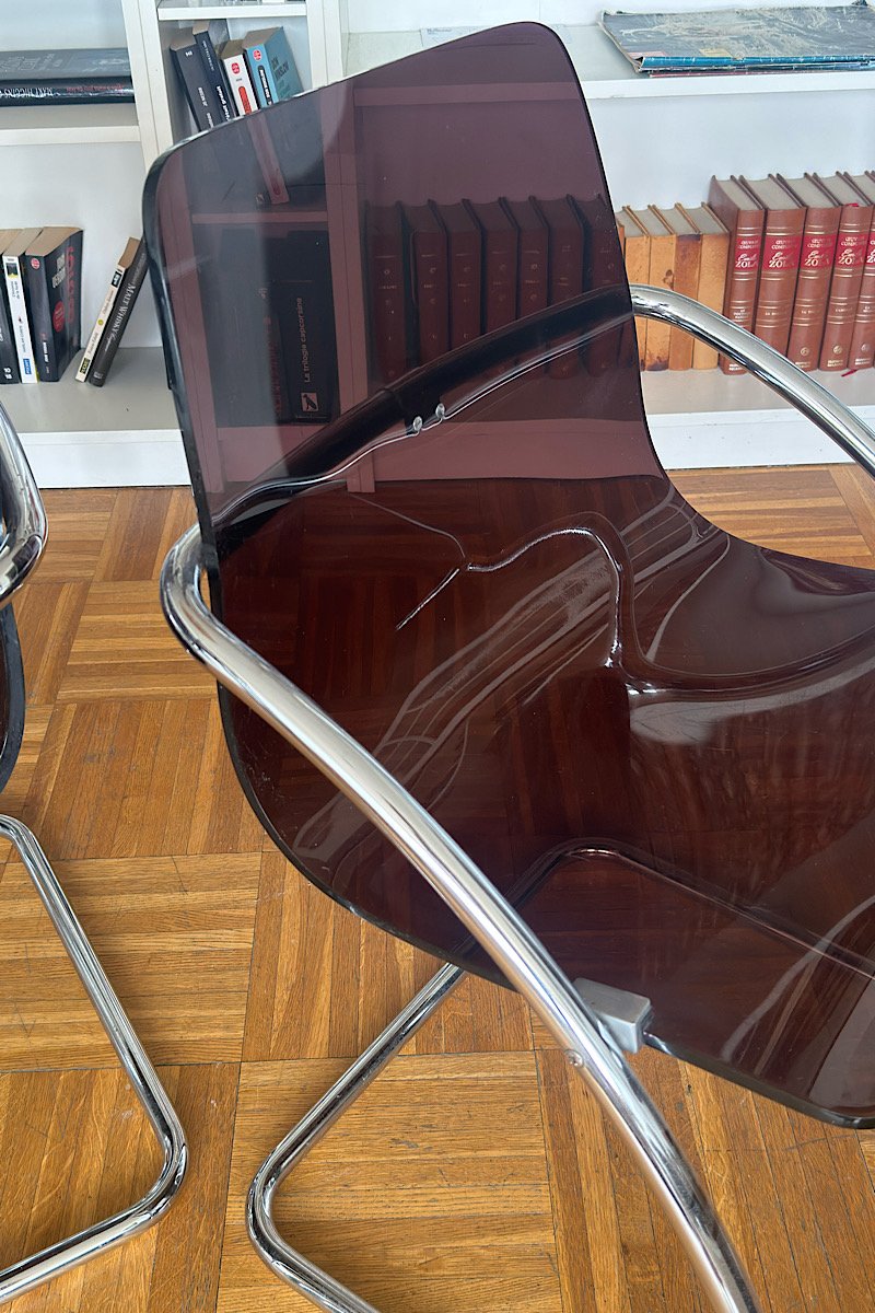 Gros plan sur une chaise design "Blooming" créée par Yves Christin, mettant en valeur la texture et la transparence de son assise en plexiglas fumé montée sur une structure métallique.
