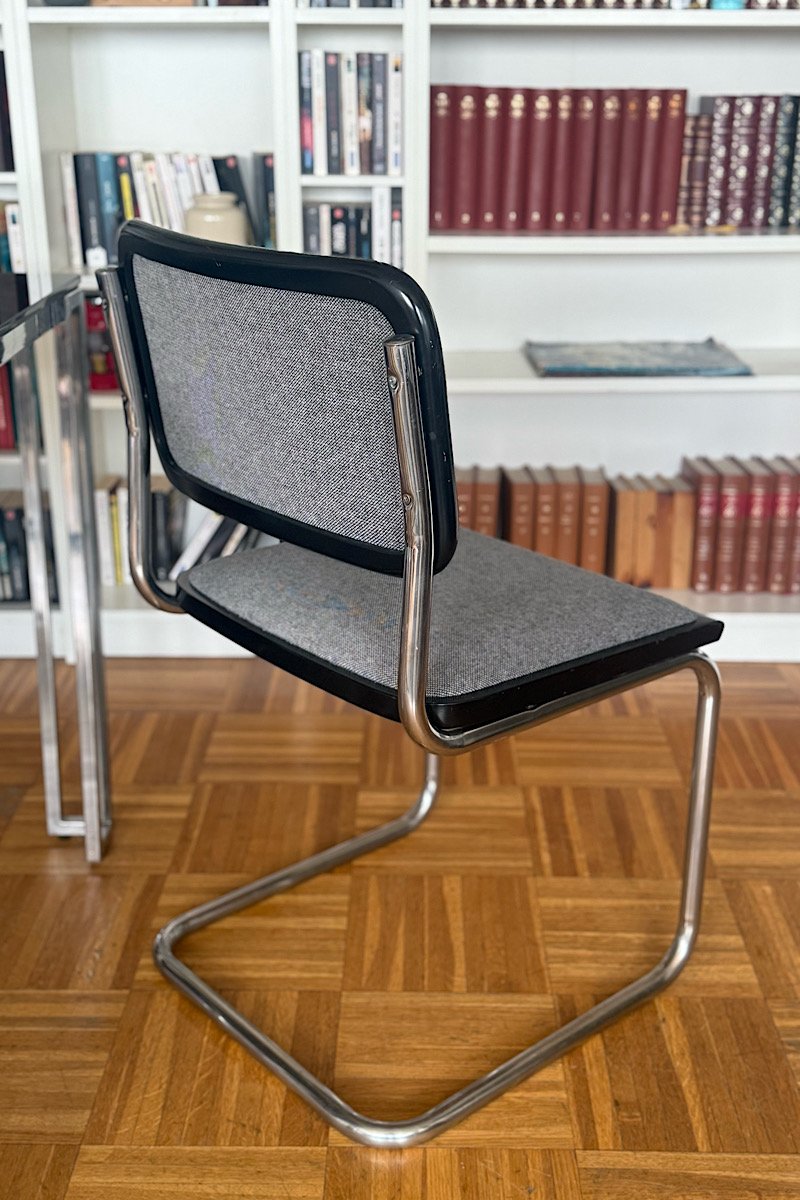 Vue de profil d'une chaise Cesca B32 de Marcel Breuer montrant sa structure en porte-à-faux en tube d'acier chromé et son assise/dossier en tissu gris