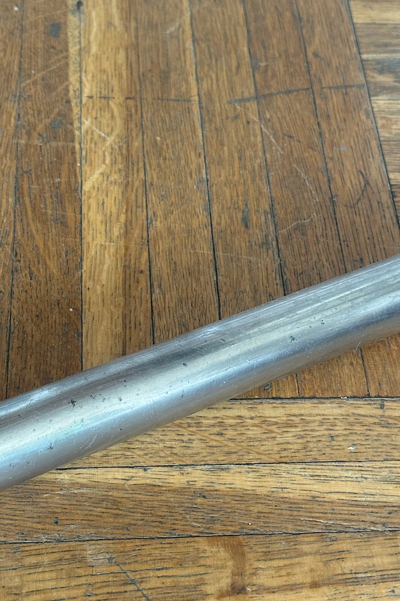 Gros plan sur un tube en acier chromé de la structure d'une chaise Cesca B32 posé sur un sol en parquet